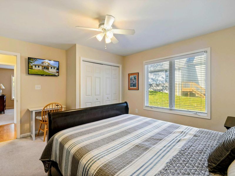 Bedroom - Alternate angle of the queen sleigh bed with wall-mounted TV, sliding closet doors, and a desk area.