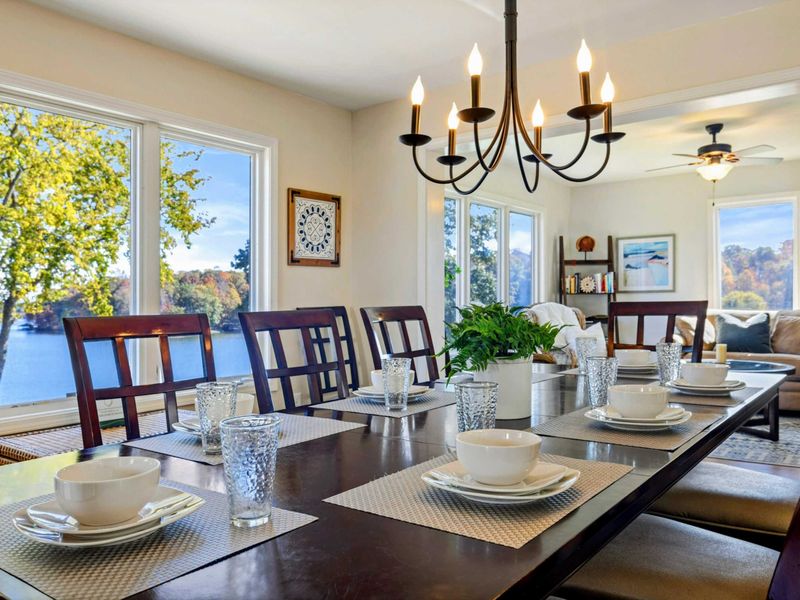 Beautifully set dining table with elegant lighting and scenic lake views, adjacent to a cozy sitting area