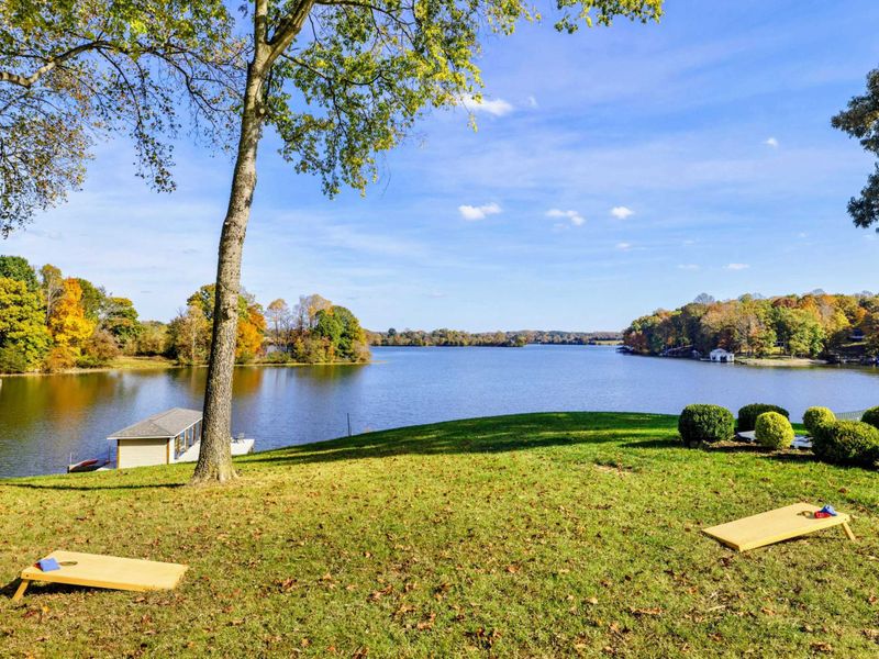 Spacious lakeside lawn with cornhole boards, perfect for outdoor games and relaxation