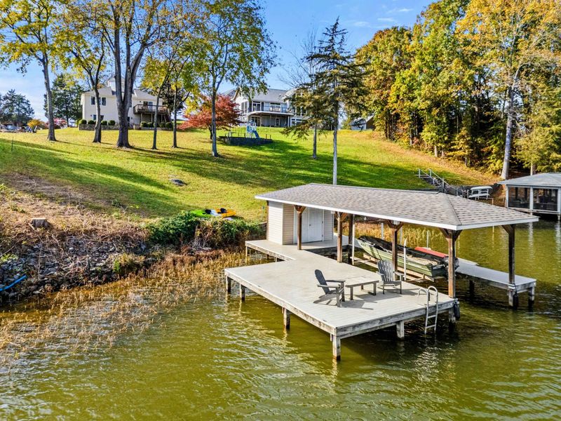 Private dock with covered boat storage and seating, set on a peaceful lakefront property