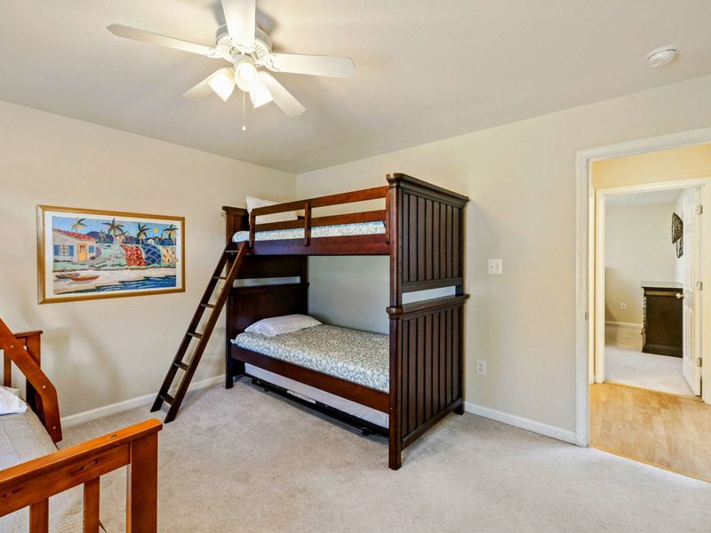 Bunk Room - Dark wood twin-over-full bunk bed with trundle pulled out, tropical art, and a doorway to the bathroom.