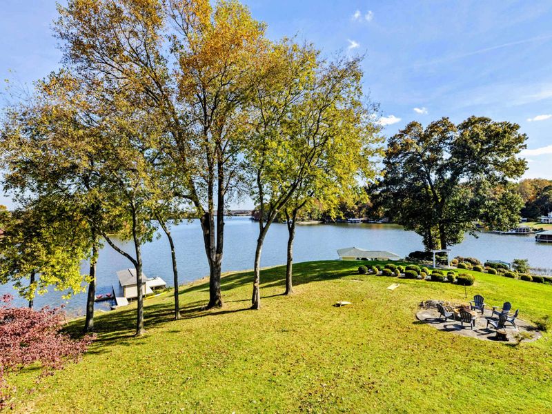 Sprawling lakeside yard with a fire pit area and beautiful waterfront views, perfect for outdoor relaxation