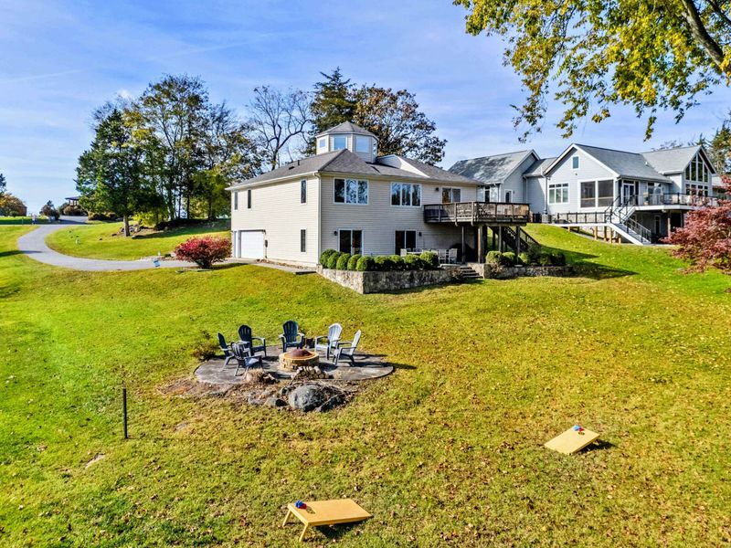 Expansive yard with a fire pit, cornhole, and a charming lakefront home, perfect for outdoor fun and relaxation