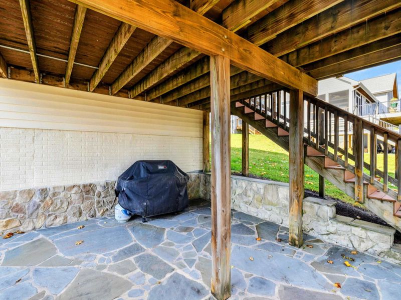 Covered stone patio with a grill, perfect for shaded outdoor cooking and dining