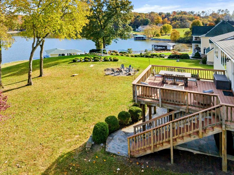 Spacious multi-level deck overlooking a large lakeside yard with a fire pit and beautiful water views