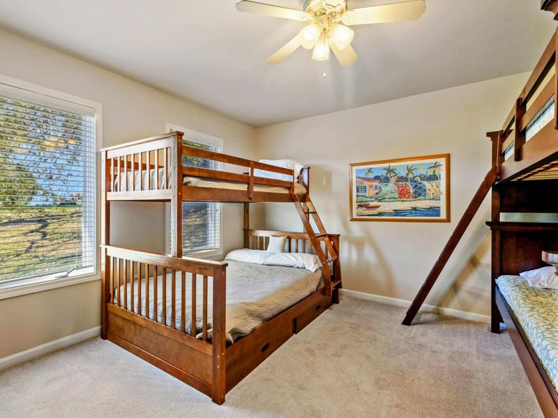 Bunk Room - Twin-over-full wood bunk bed and a dark twin-over-full bunk with trundle, tropical painting, and ceiling fan.