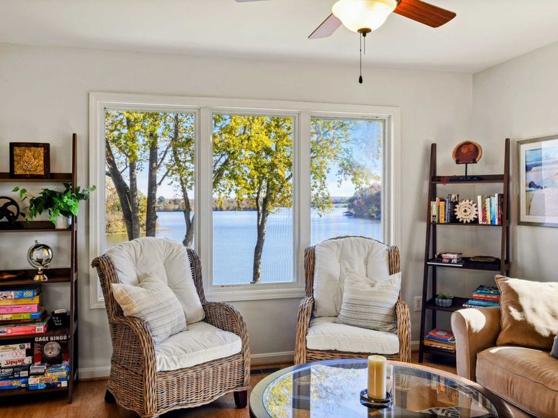 Cozy sitting nook with plush chairs, bookshelves, and stunning lake views through large windows