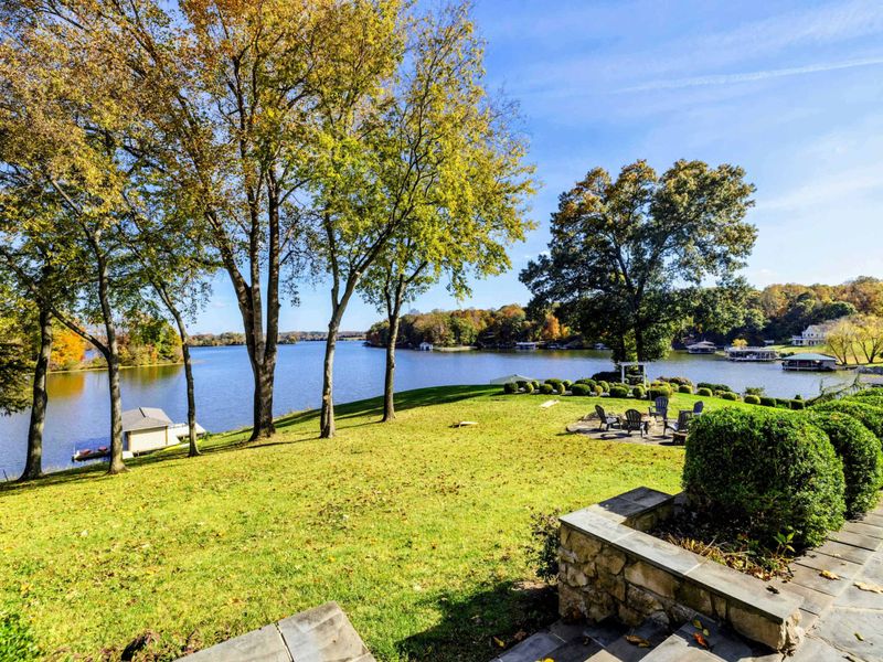 Beautiful lakeside yard with a fire pit area, shaded by trees and perfect for outdoor relaxation