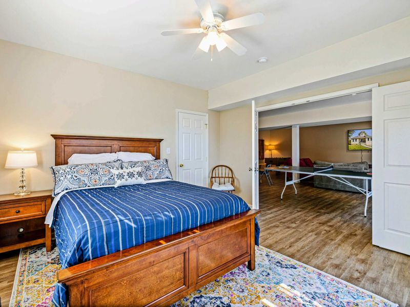 Bedroom - King bed with blue striped bedding, traditional wood furniture, sliding barn doors open to the game room and lounge.