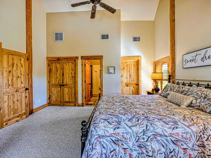 Sleep peacefully in this stunning loft-style bedroom featuring vaulted ceilings, exposed wooden beams, and abundant natural light for a cozy retreat.