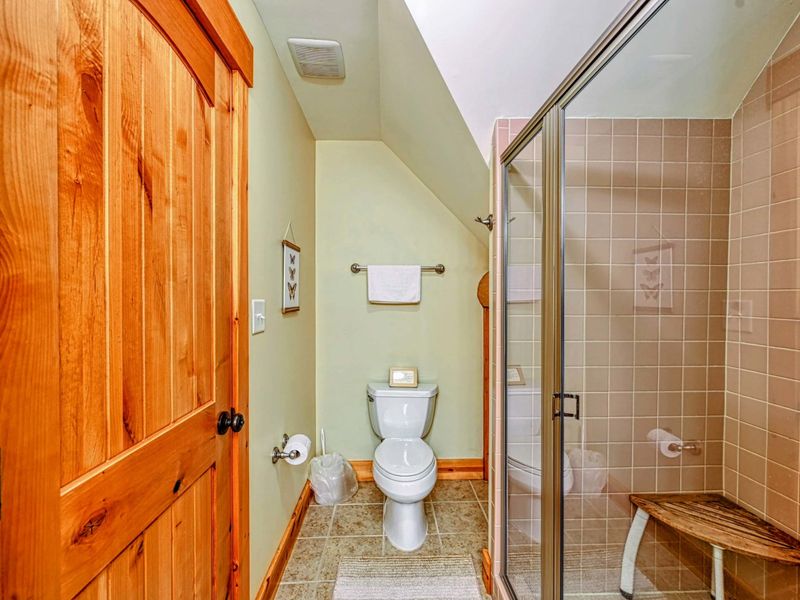 Step into this inviting bathroom featuring a glass-enclosed tiled shower, natural wood accents, and a cozy, functional design.