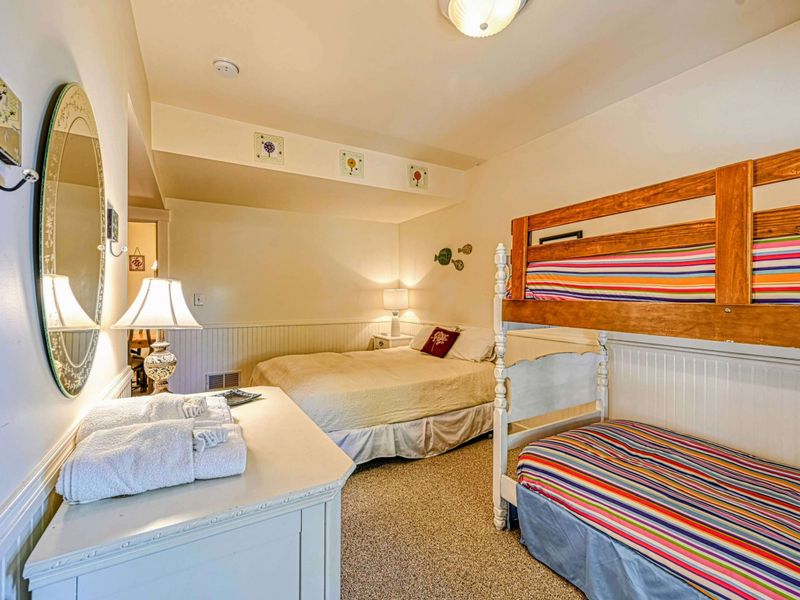Perfect for families, this cozy bedroom features a queen bed, charming bunk beds, and soft lighting for a comfortable stay.