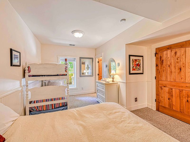 Perfect for families, this cozy bedroom features a queen bed, charming bunk beds, and soft lighting for a comfortable stay.