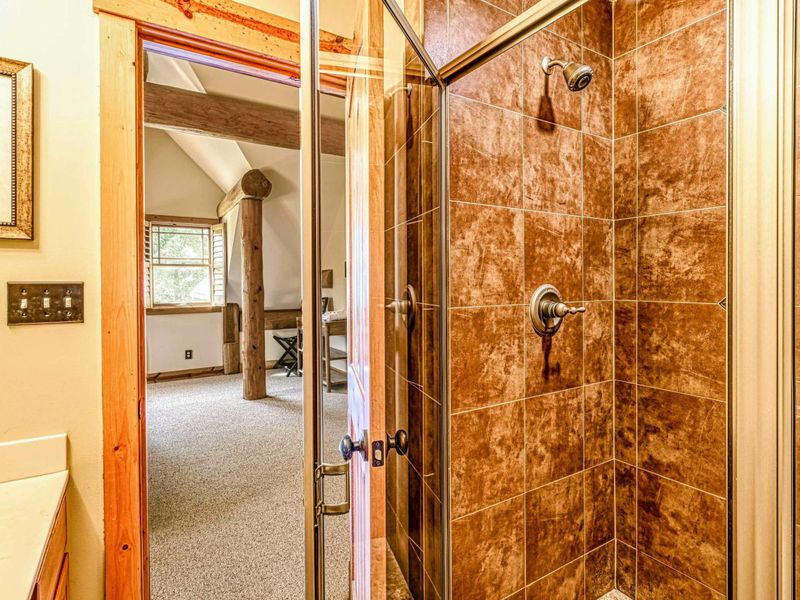 Freshen up in this cozy bathroom featuring a tiled glass-enclosed shower, rustic wood accents, and modern amenities for your comfort.