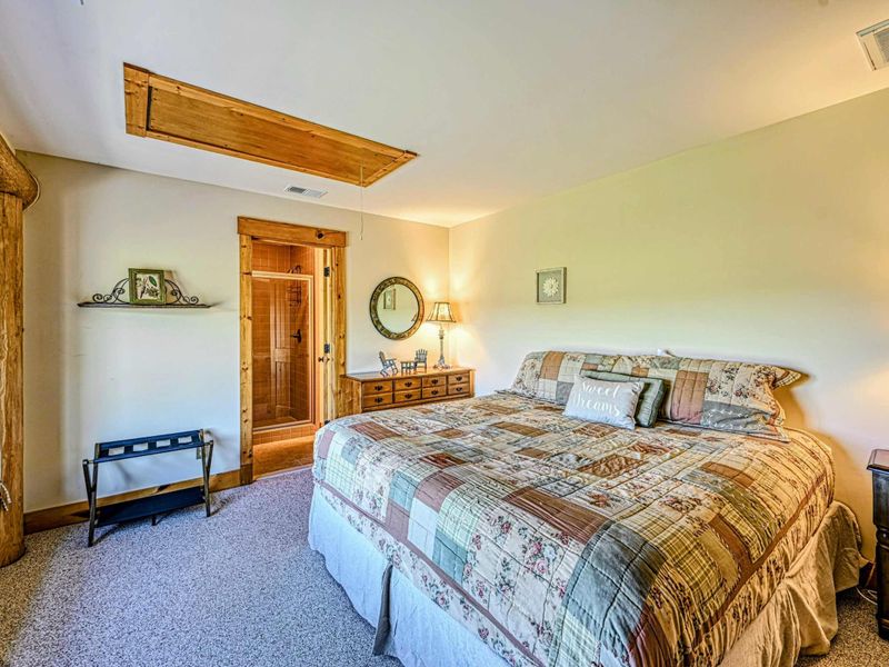 Relax in this cozy bedroom featuring rustic wood accents, a comfortable bed, and a charming window seat with scenic views.