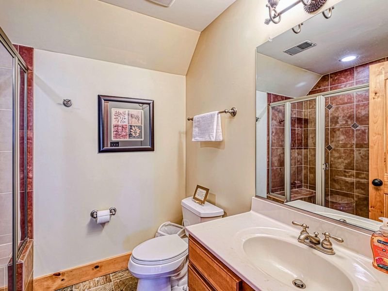 Freshen up in this cozy bathroom featuring a tiled glass-enclosed shower, rustic wood accents, and modern amenities for your comfort.