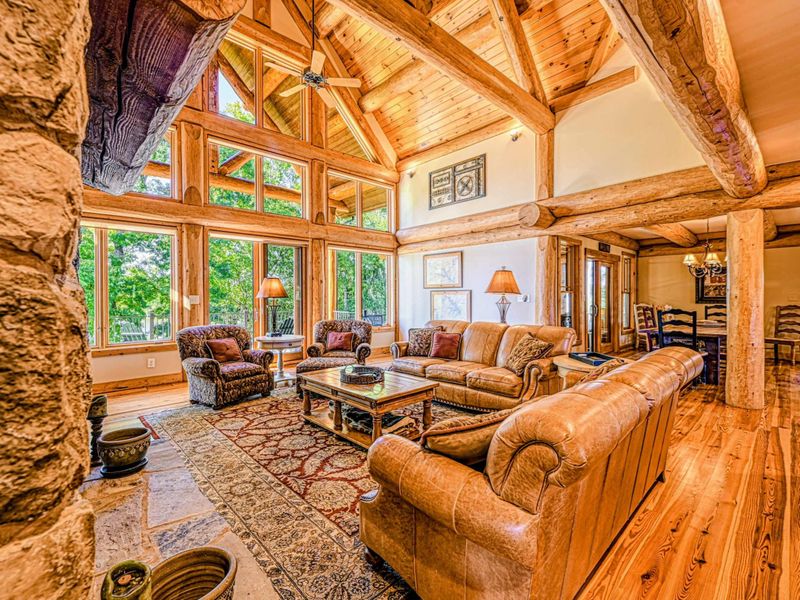 Screened Porch - Wicker seating and a bistro table under a ceiling fan, all wrapped in timber beams with lake views through the screens.