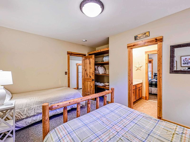 Rest in this cozy bedroom featuring a charming wooden bed frame, an additional twin bed, and soft lighting for a peaceful stay.