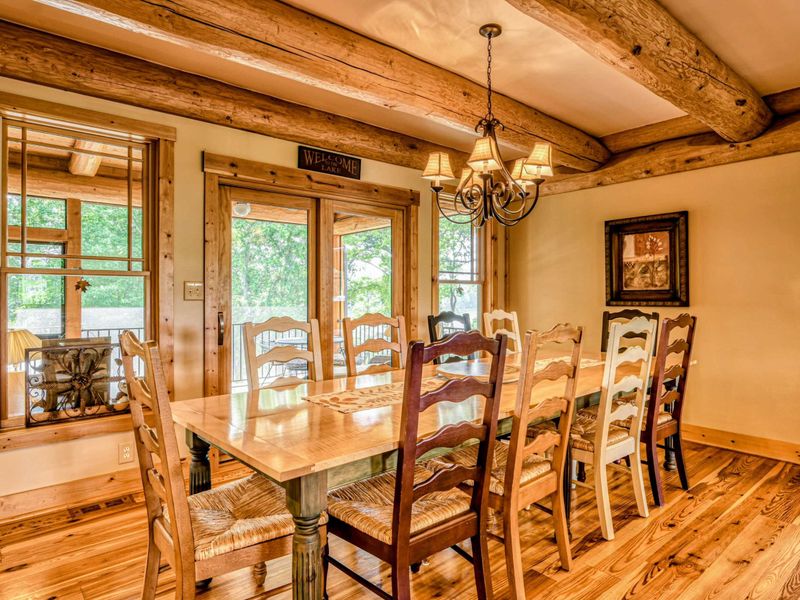 Cozy and elegant log cabin interior featuring a grand stone fireplace, high vaulted ceilings, and warm natural lighting
