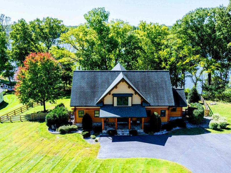 Welcome to this charming lakeside home featuring a rustic exterior, manicured landscaping, and a warm, inviting front porch.