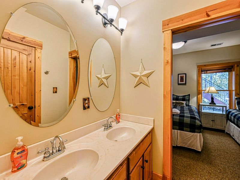 Enjoy the convenience of a double vanity in this warm and inviting bathroom, complete with rustic wood accents and modern fixtures.