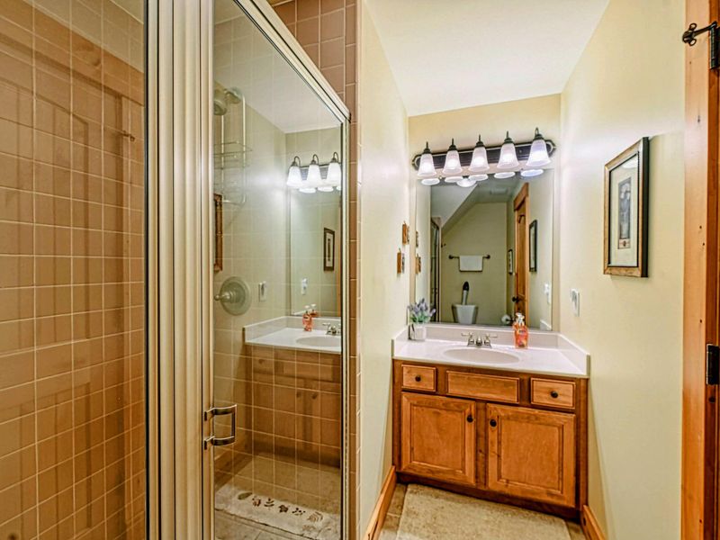 Step into this inviting bathroom featuring a glass-enclosed tiled shower, natural wood accents, and a cozy, functional design.