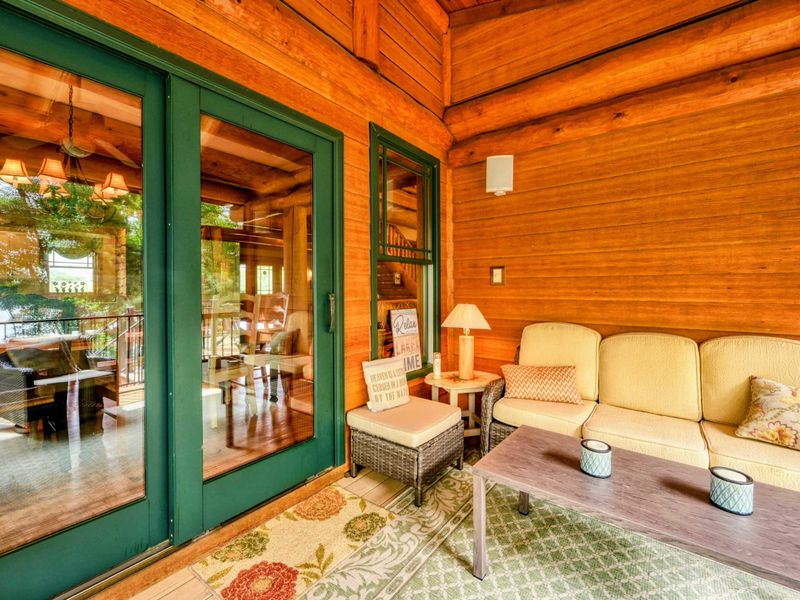 Exterior - Teal Adirondack chairs line the rear deck beneath the massive timber A-frame entry with floor-to-ceiling windows.