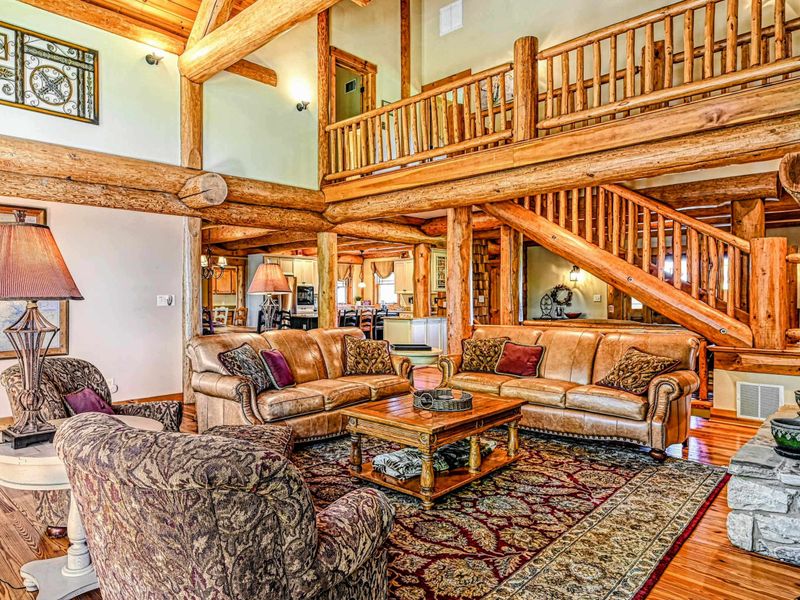 Deck - Green Adirondack chairs and lounge seating line the expansive deck overlooking the lake through the trees.