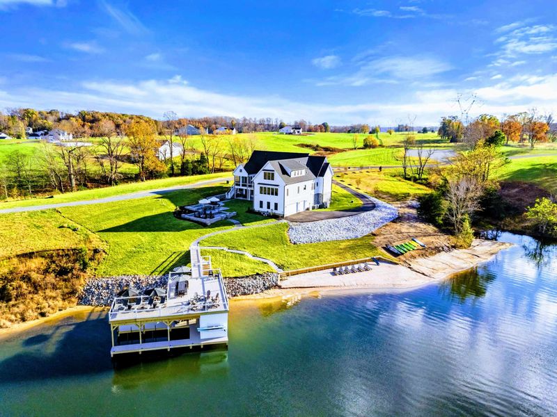 Exterior - Lakeside estate viewed from the water with beach, dock, and tiered outdoor spaces.