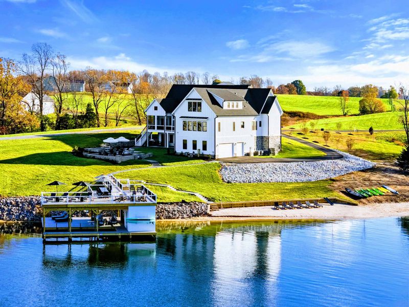 Backyard - Stone patio with firepit seating, plunge pool, and lake views beyond the sloped lawn.