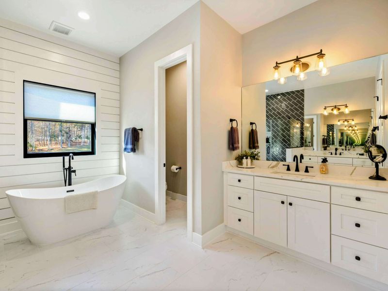 Primary Bath - Freestanding soaking tub, glass-enclosed shower, and dual vanity.