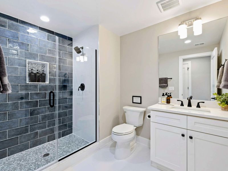 Bathroom 6 - Glass shower with dark subway tile, modern vanity, and clean lines.