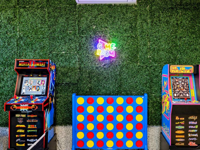 Game Room - Arcade corner with classic cabinets, giant Connect Four, and neon art.