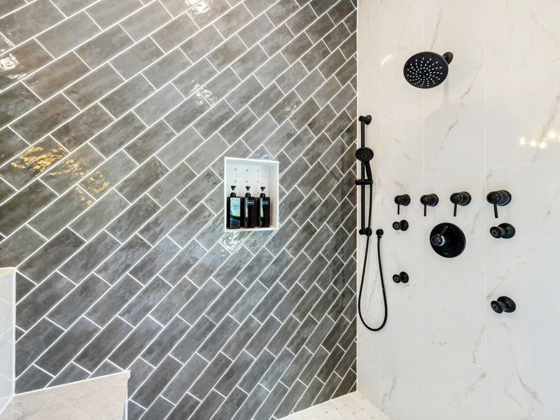 Primary Bath - Walk-in shower with gray tile, built-in shelving, and rain showerhead.