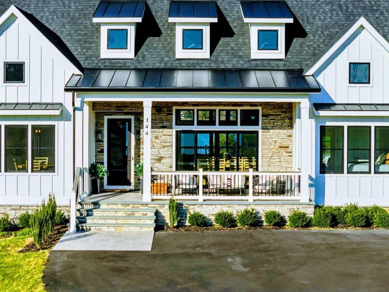 Exterior - Front porch with stone columns, metal roof, and oversized windows.