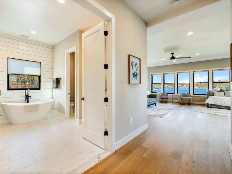 Primary Suite - Open transition between the bathroom and bedroom with freestanding tub in view.