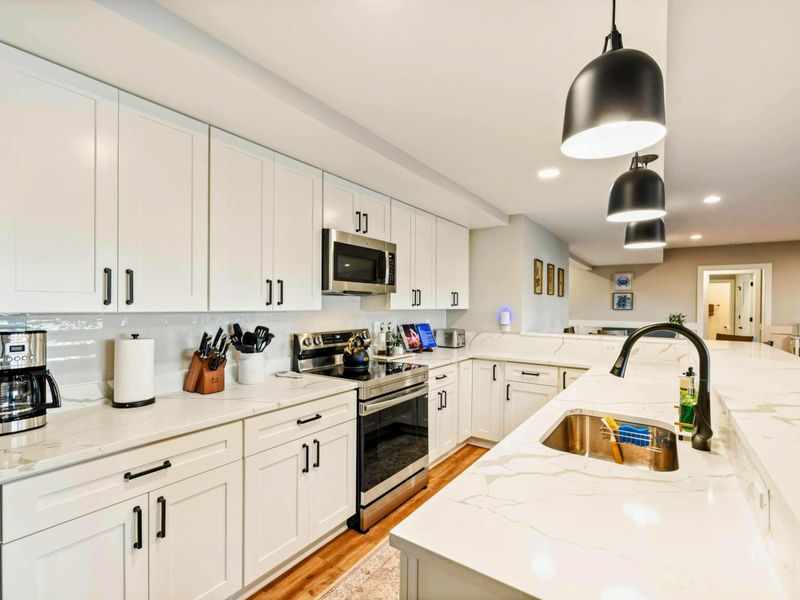 Lower Kitchen - Full kitchen with white cabinetry, quartz countertops, and pendant lighting.