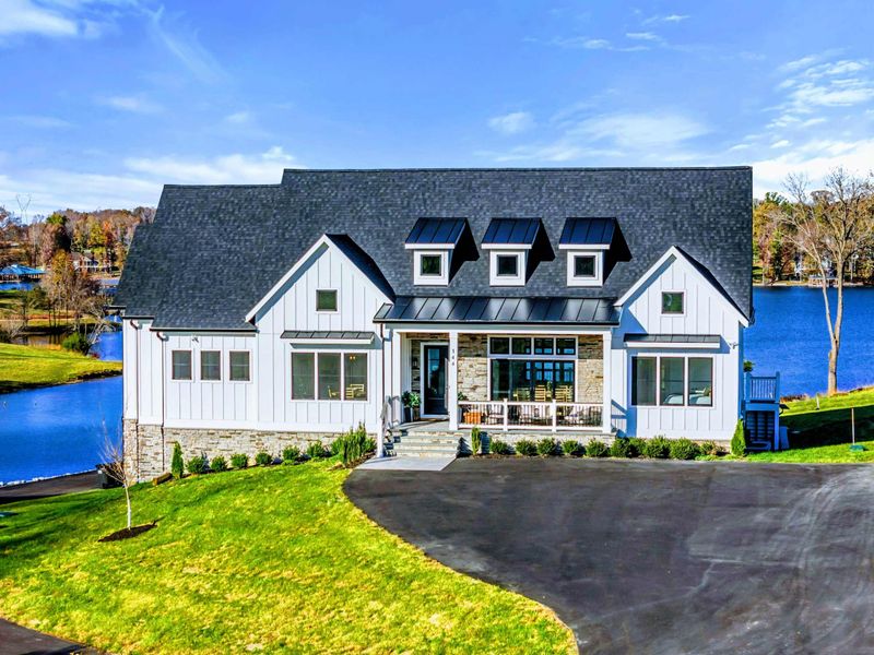 Exterior - Wider view of the lakefront facade with tiered decks and green lawn.