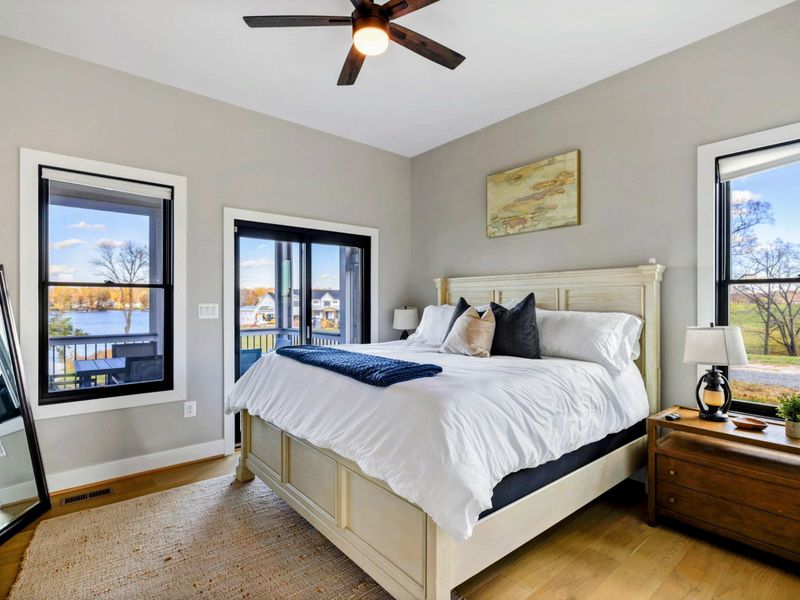 Bedroom 4 - Queen bed with wall-mounted TV and lake views from a private balcony.