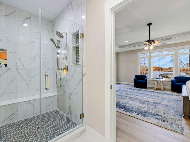 Luxurious en suite bathroom with a freestanding soaking tub, double vanity with navy cabinets, a walk-in shower, and elegant finishes.