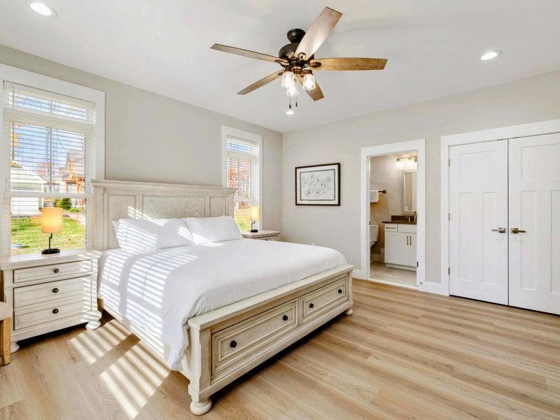 Bright and airy bedroom with a king-sized bed, elegant furnishings, large windows, and an en suite bathroom.