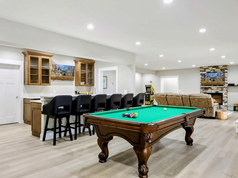 Entertainment area with a pool table, bar seating, and a cozy lounge featuring a stone fireplace, perfect for relaxing and socializing.