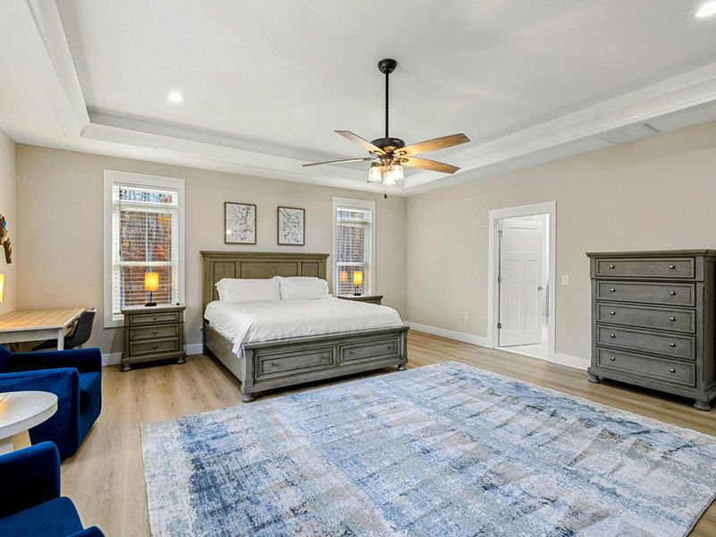 Elegant Primary Bedroom featuring a king-sized bed, stylish furnishings, a spacious layout, natural light from large windows, and an en suite bathroom for added convenience.
