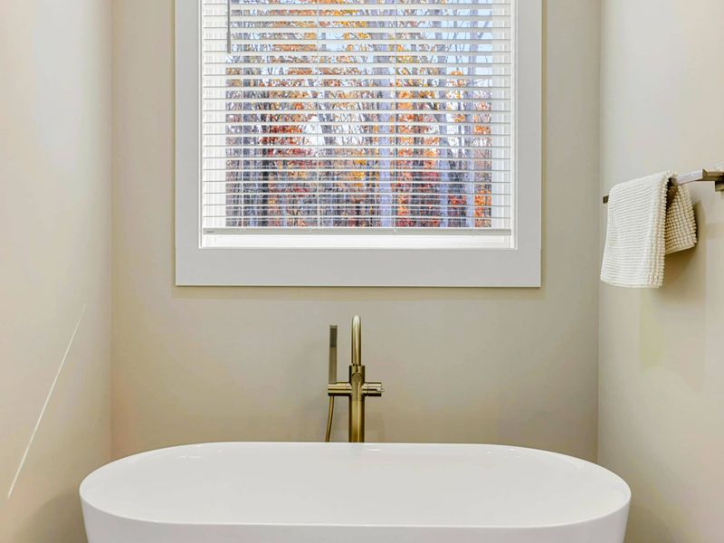 Luxurious en suite bathroom with a freestanding soaking tub, double vanity with navy cabinets, a walk-in shower, and elegant finishes.