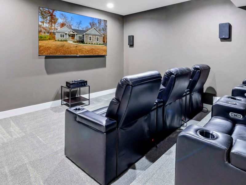 Enjoy a cozy and modern home theater experience with plush recliner seating and a large wall-mounted screen in this entertainment room.