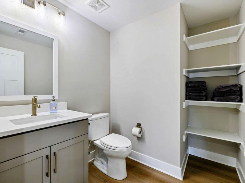 Modern bathroom with sleek fixtures, ample counter space, and built-in shelving for towels and storage.