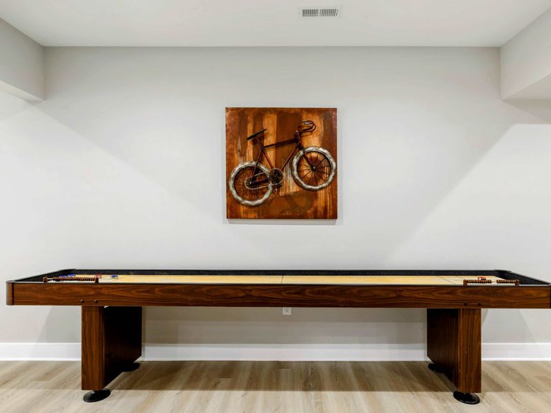 Stylish game area featuring a shuffleboard table and modern decor, perfect for fun and relaxation.