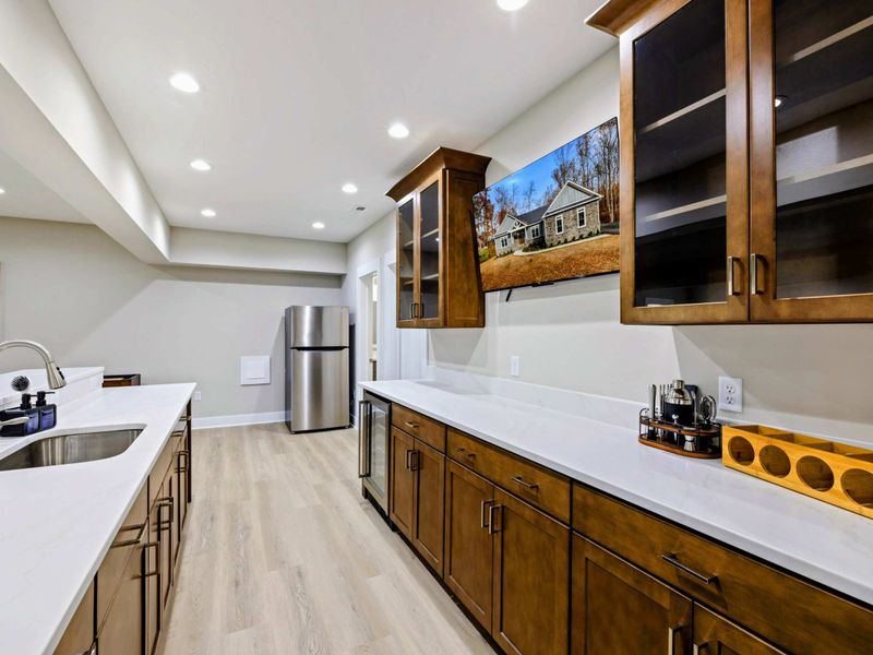 Spacious bar area with elegant wooden cabinetry, a sink, and plenty of counter space, seamlessly connected to the entertainment room.