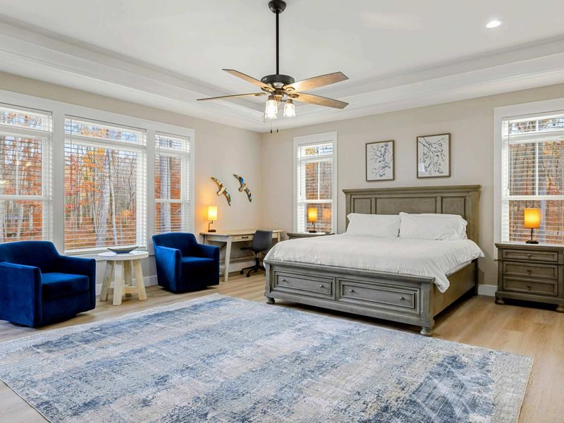 Elegant Primary Bedroom featuring a king-sized bed, stylish furnishings, a spacious layout, natural light from large windows, and an en suite bathroom for added convenience.