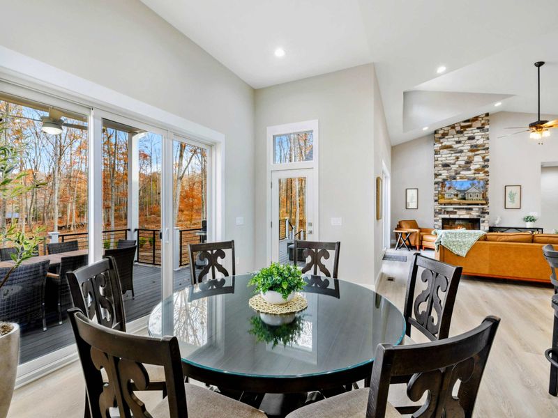 Cozy dining area with elegant seating, large windows, and sliding doors leading to an outdoor deck with beautiful views.
